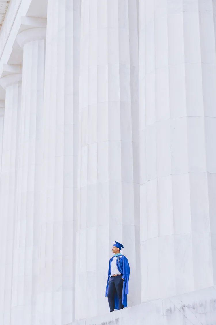 A graduate standing among monumental white columns