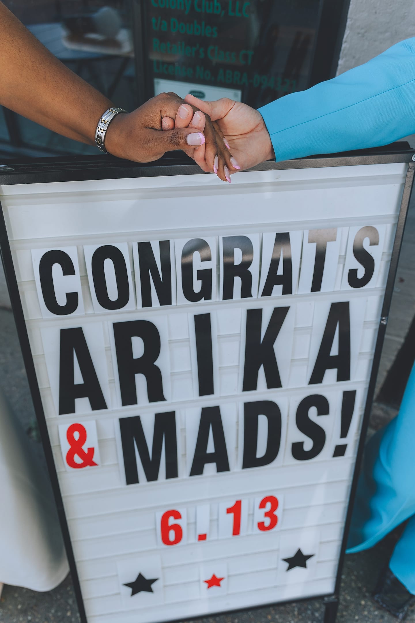 Couple clasps hands over a Congrats Arika and Mads letterboard sign at their DC wedding