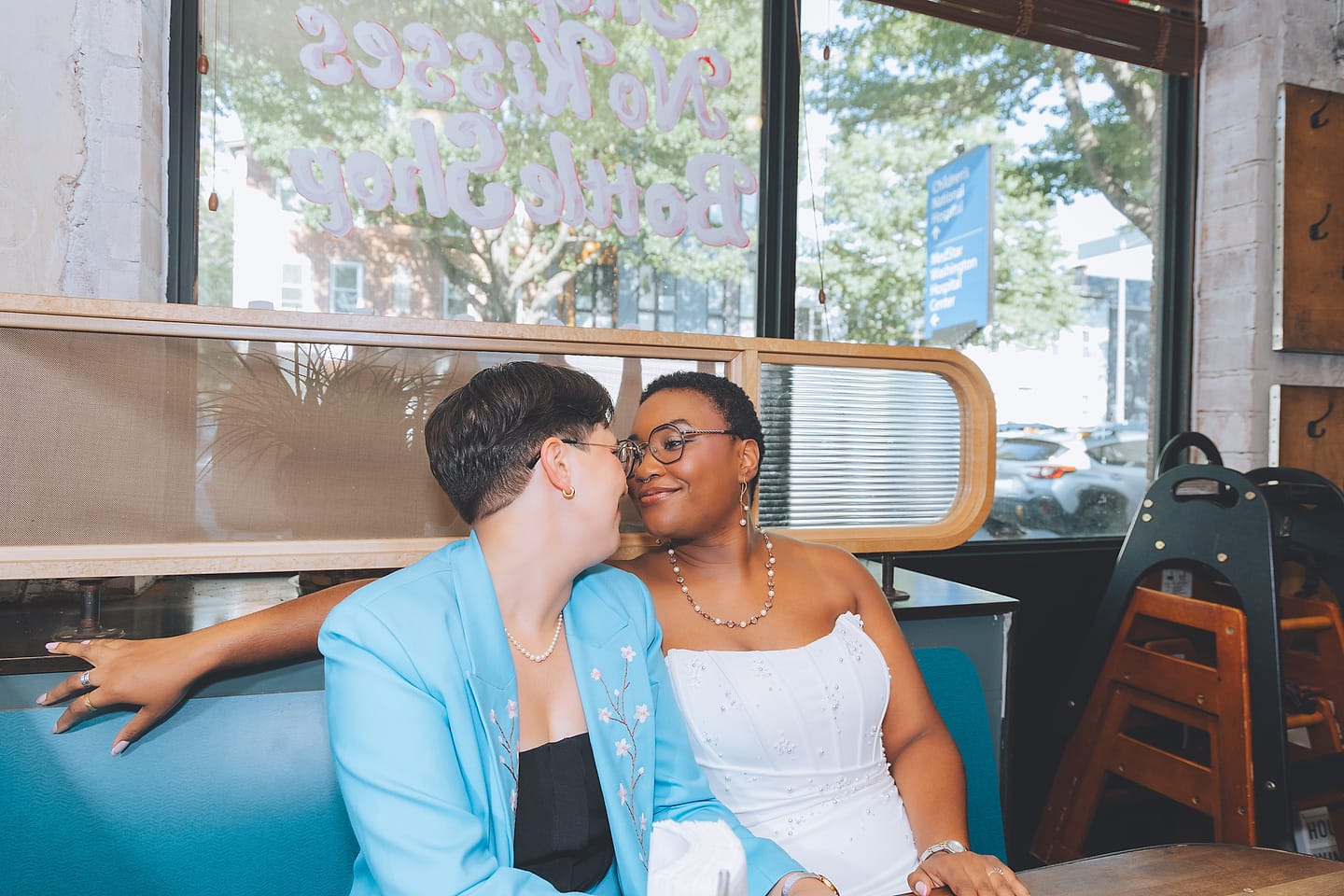 Newlywed brides kiss in a restaurant booth at their Washington DC wedding