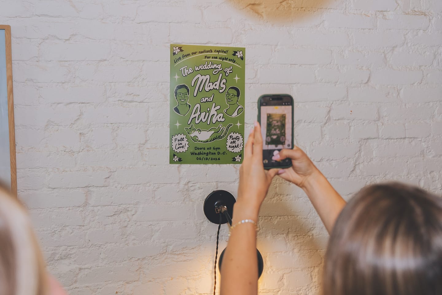 Guest photographs Arika and Madeline's illustrated wedding poster at a Washington DC venue