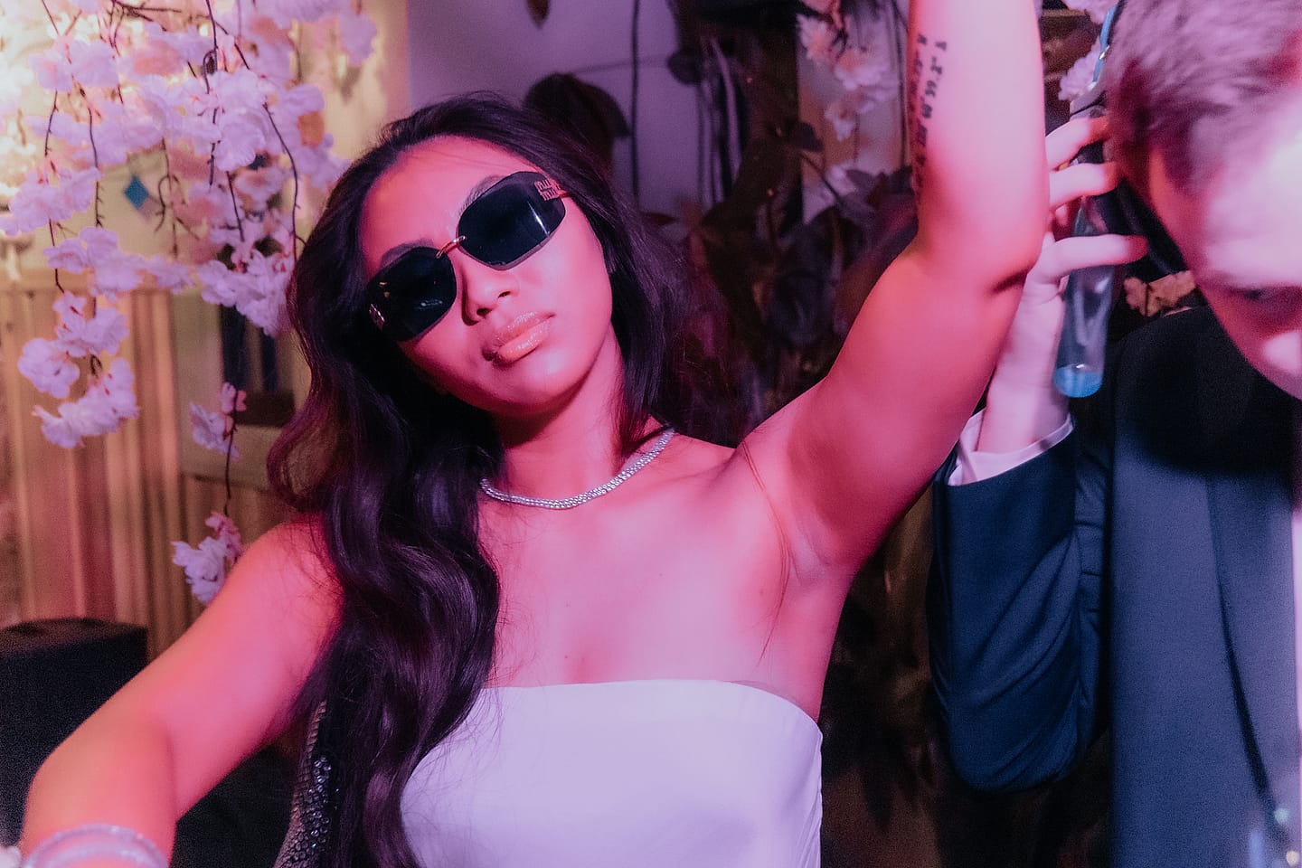 Bride in sunglasses poses under cherry blossoms at a stylish Washington DC wedding reception