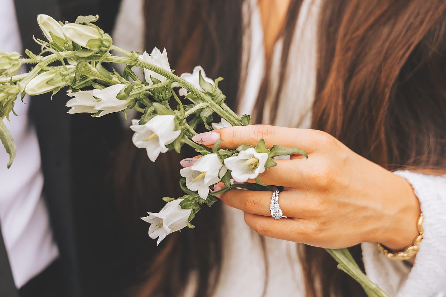 Bride holds white bellflowers with her wedding ring visible at a Washington DC wedding