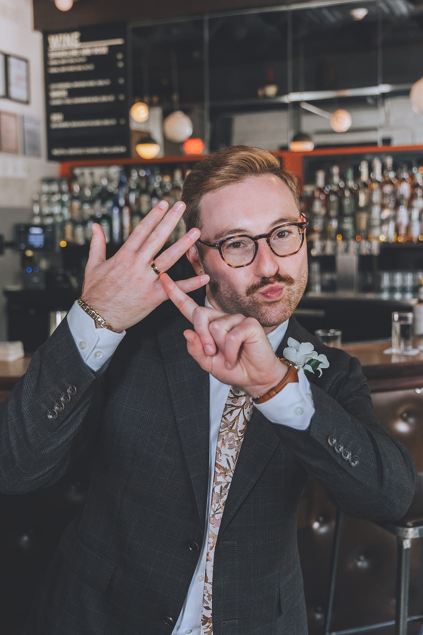 A smiling groom strikes a playful pose at the All Souls bar counter in Washington, D.C.