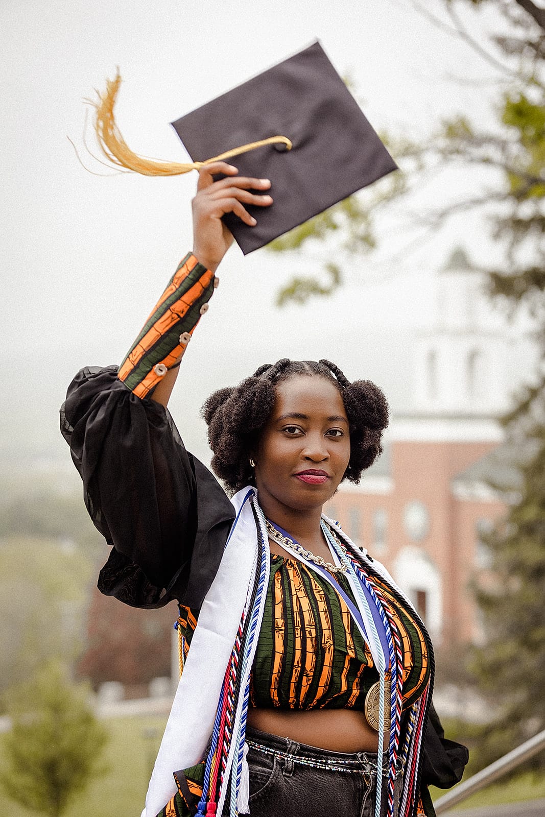 A graduate posing outside a stately college building