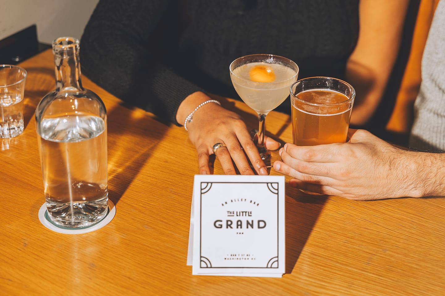 Newlyweds' hands with cocktails at The Little Grand bar on their wedding day